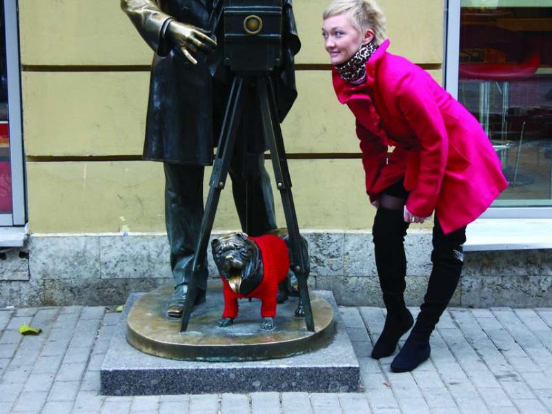 Собаке, которая сидит у ног памятника фотографу, одели вязаный джемпер. Памятник фотографу на Малой Садовой улице.